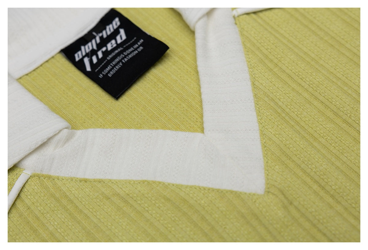 Close-up of the pale yellow shirt's white collar and placket beside its black neck label.