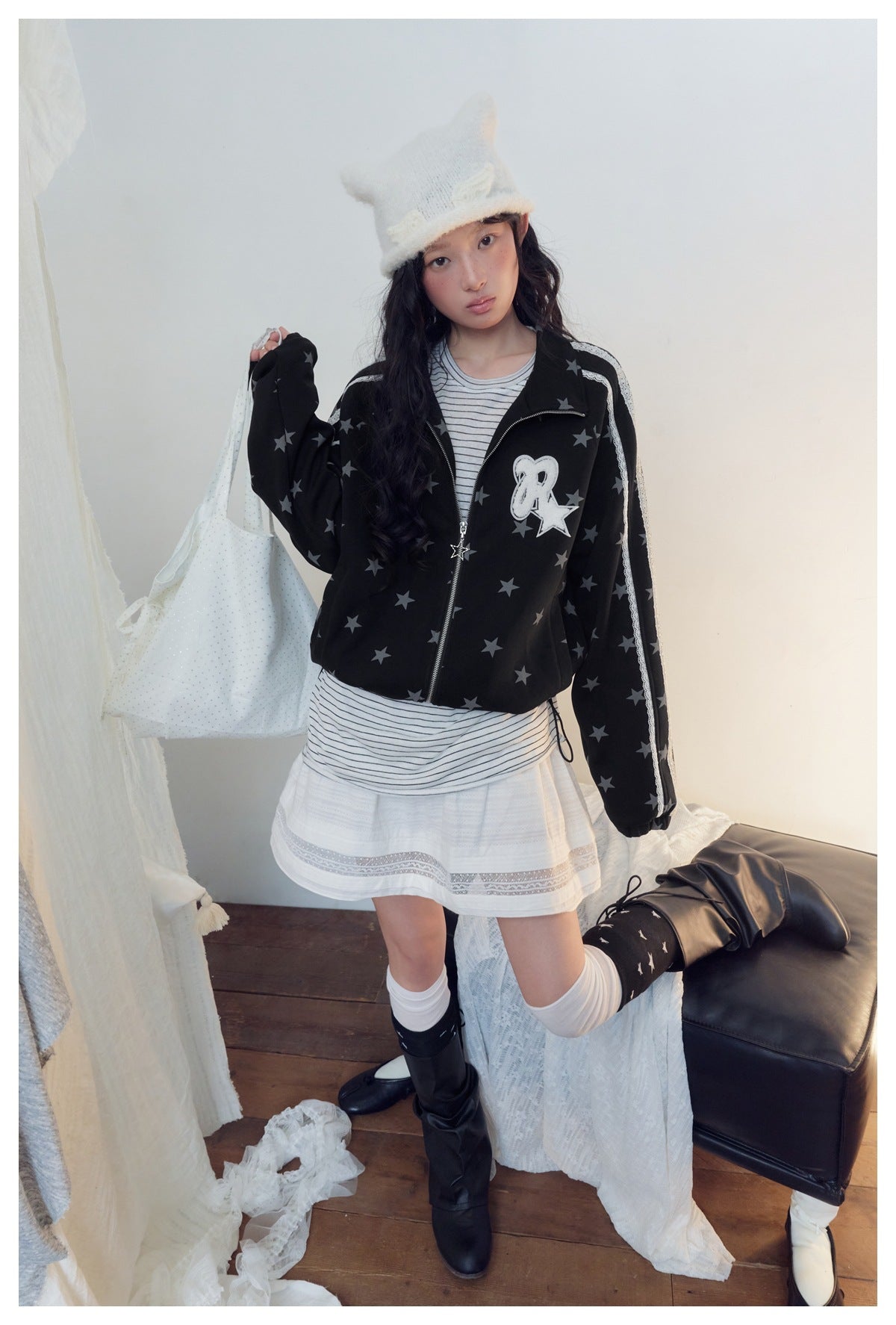 Model wearing a black jacket with gray stars, white lace sleeve stripes and a chest patch, paired with a striped top and