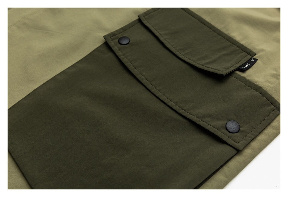 Close-up of an olive garment's dark patch pocket with a flap, two black snaps, and a small side tag.