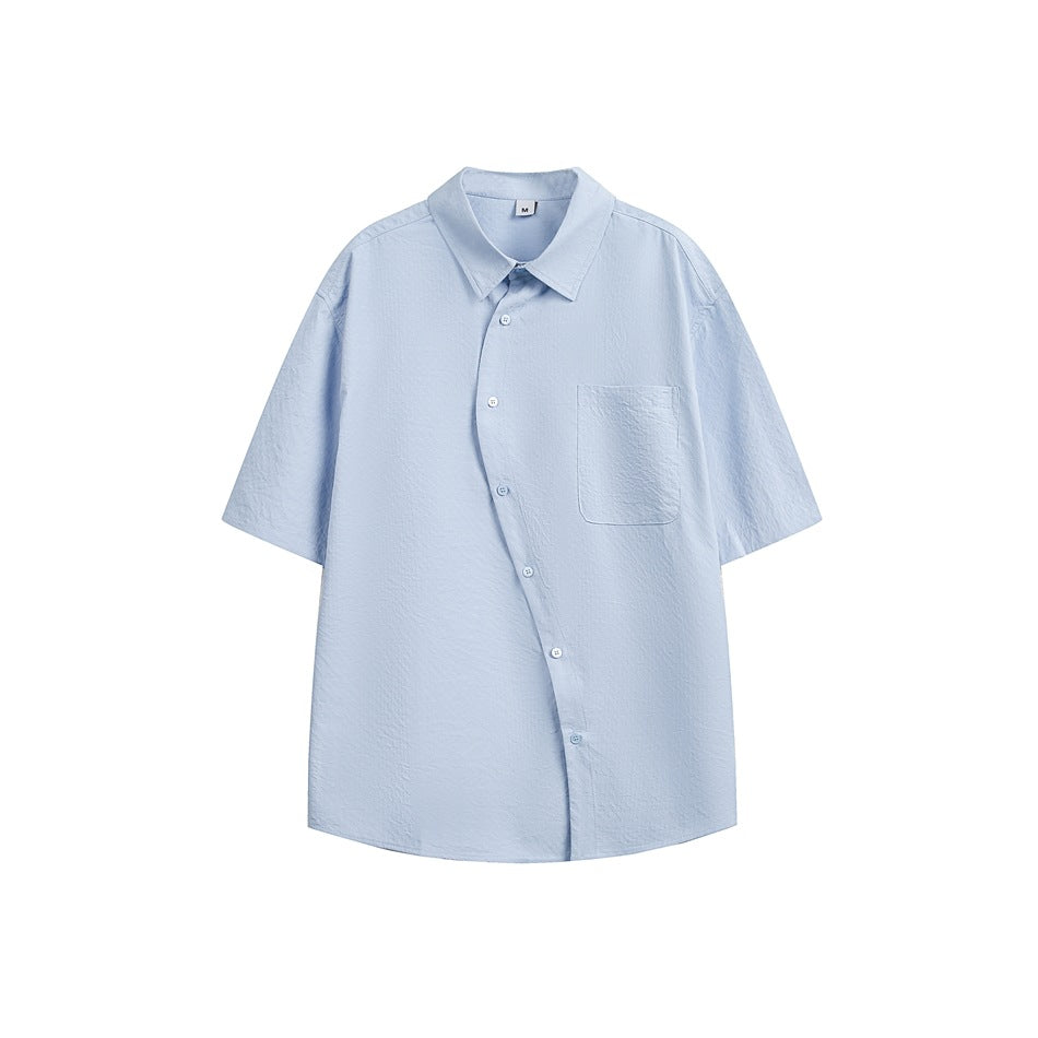 Light blue short-sleeve shirt with an asymmetric diagonal button front and chest pocket, flat lay on white