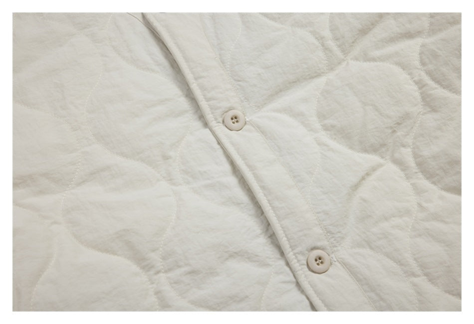 Close-up of the ivory jacket's circular quilting and two buttons on the front placket.
