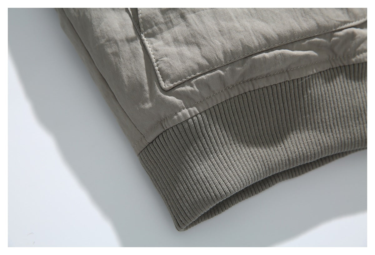 Close-up of the taupe jacket's wide ribbed hem and lower edge of a flap pocket.