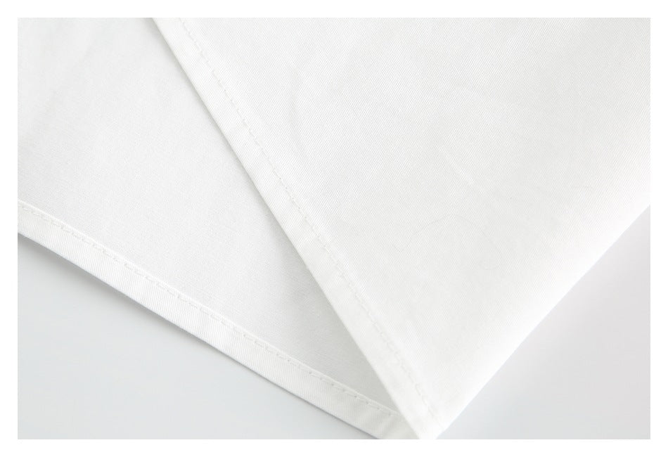 Close-up of a white garment's stitched edge and intersecting seams.