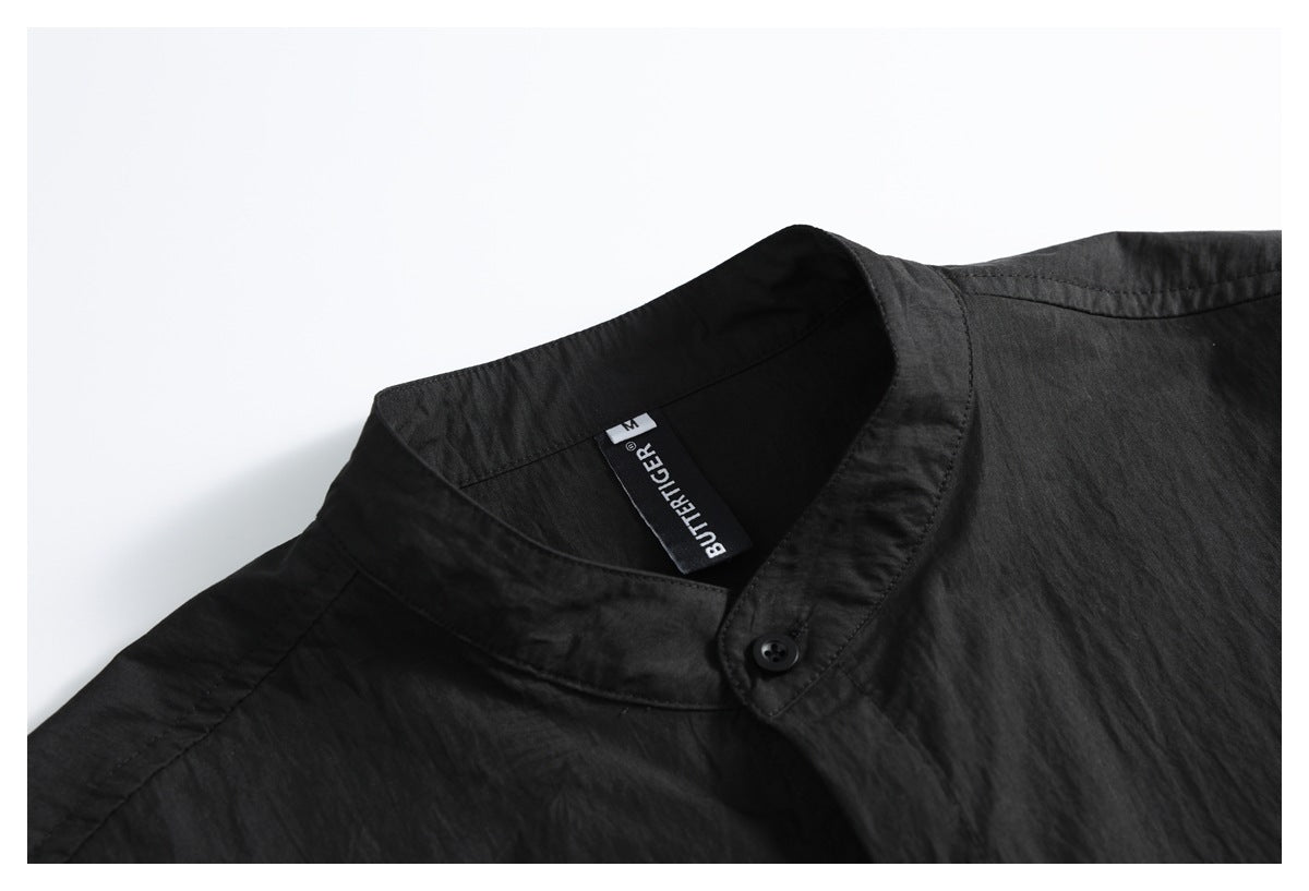 Close-up of a black shirt's band collar, button, and sewn-in neck label.