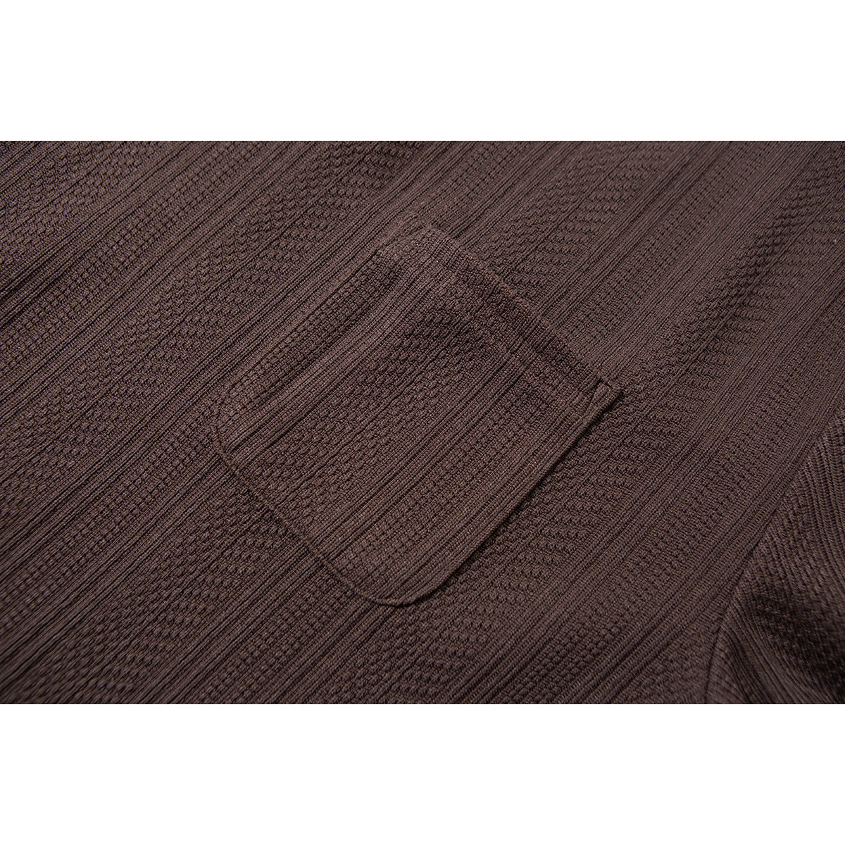 Close-up of a dark brown textured shirt's rectangular chest pocket and stitched edges.