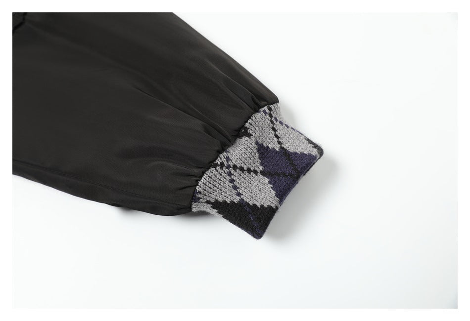 Close-up of a black sleeve ending in a gray, black, and purple patterned knit cuff.