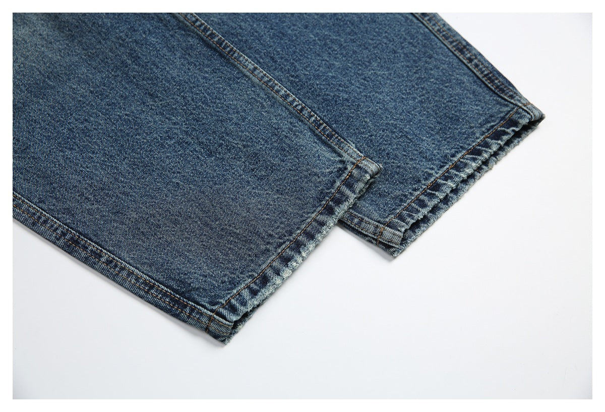 Close-up of the lower legs and stitched hems of blue jeans laid flat.