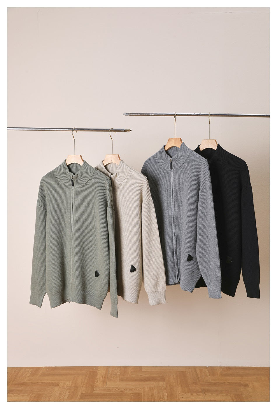 Four ribbed knit zip cardigans in gray-green, beige, gray and black hanging on a rail