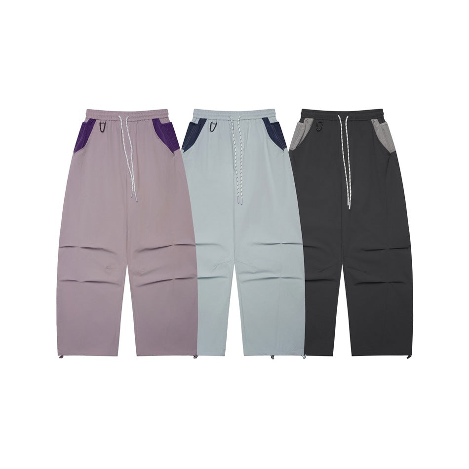 Front view of loose drawstring pants in mauve, pale blue-gray, and charcoal with contrasting pocket panels.