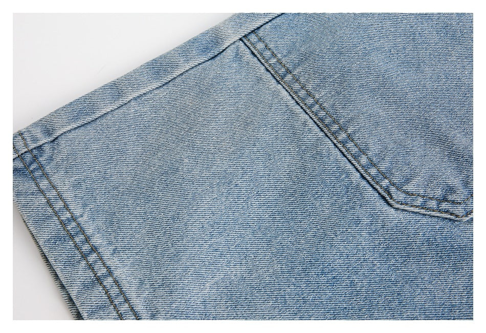 Close-up of light blue denim with diagonal seam stitching and a large stitched panel.