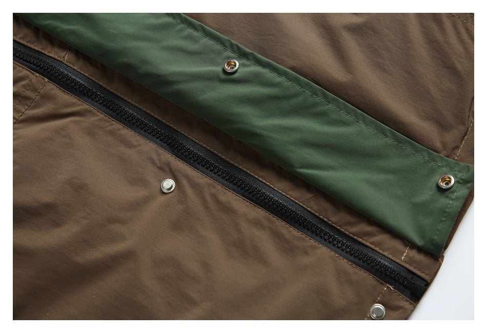 Close-up of a brown jacket front showing a black zipper beneath a dark green snap-fastened storm flap.