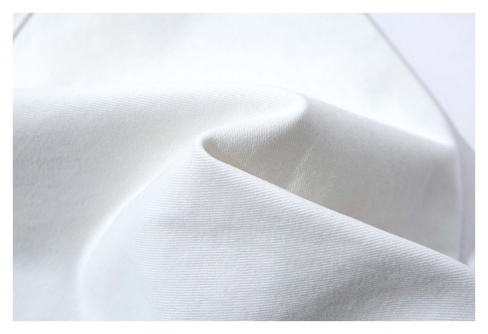 Close-up of white garment fabric draped to show its fine diagonal weave.