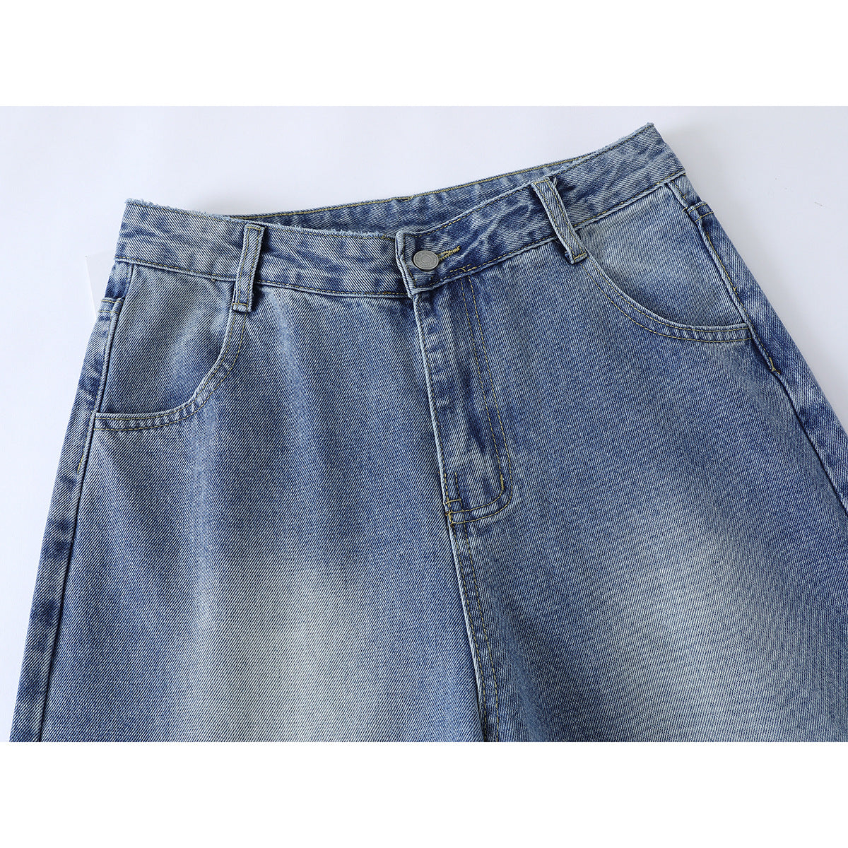 Close-up of the front waistband, button, fly and pockets of light blue jeans.