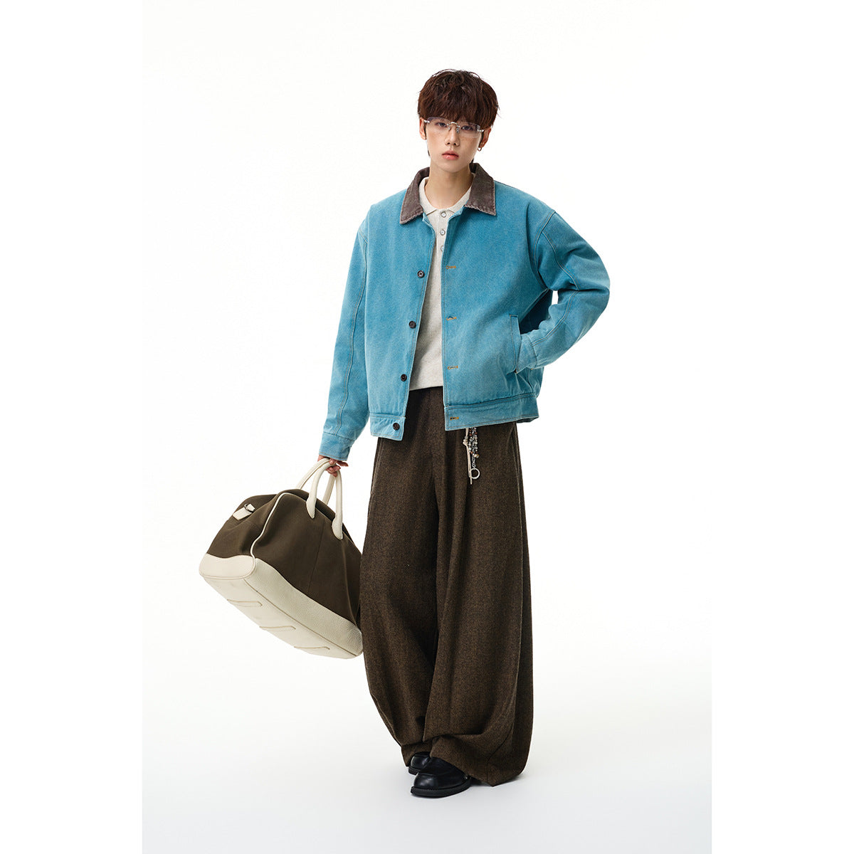 Full-length view of a model wearing a teal button-front jacket with a brown collar and dark wide-leg trousers.