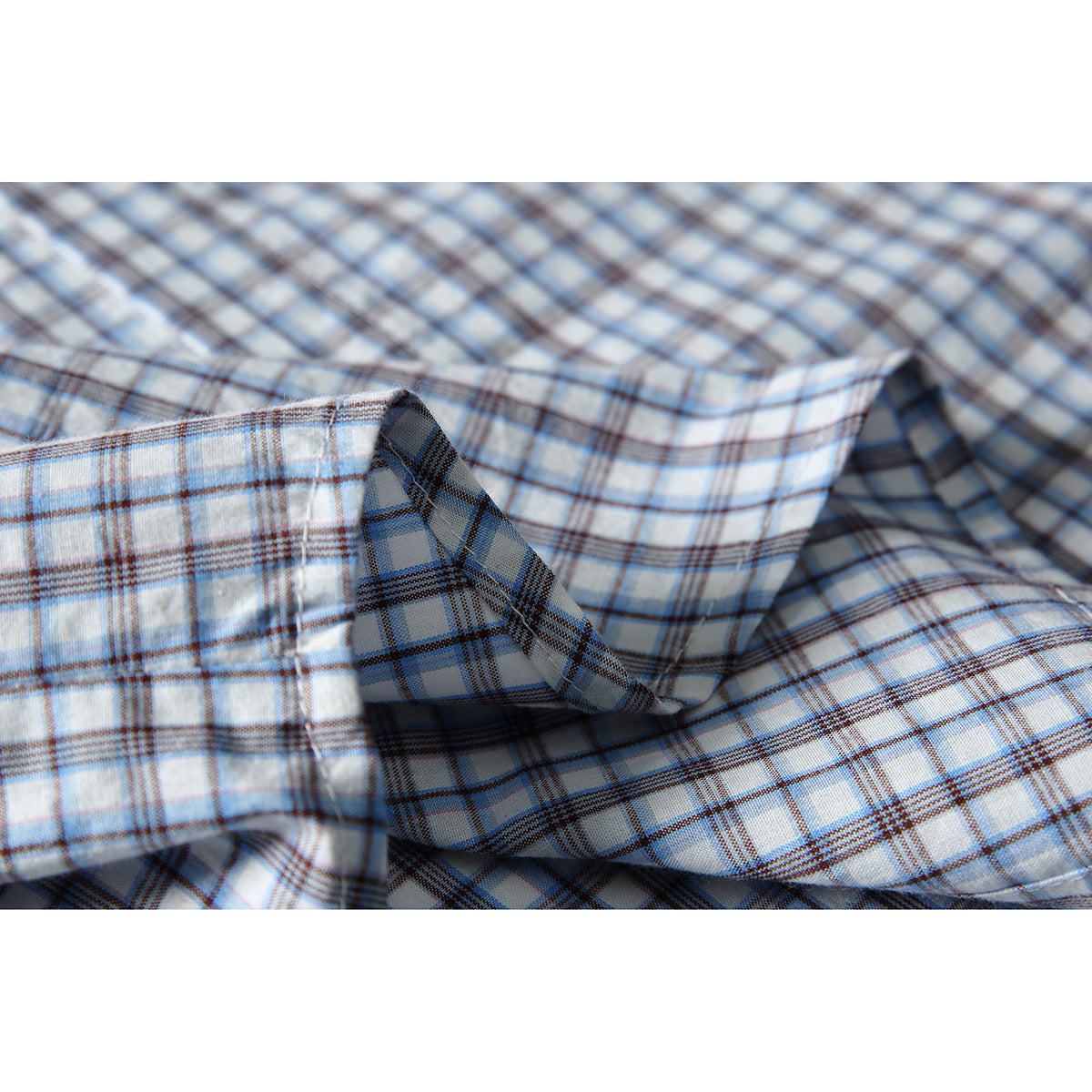 Macro view of white fabric with blue and brown plaid, folded to show its pattern and texture.