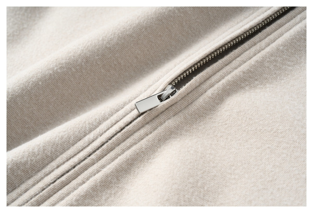 Close-up of a diagonal silver zipper on beige heathered fabric.