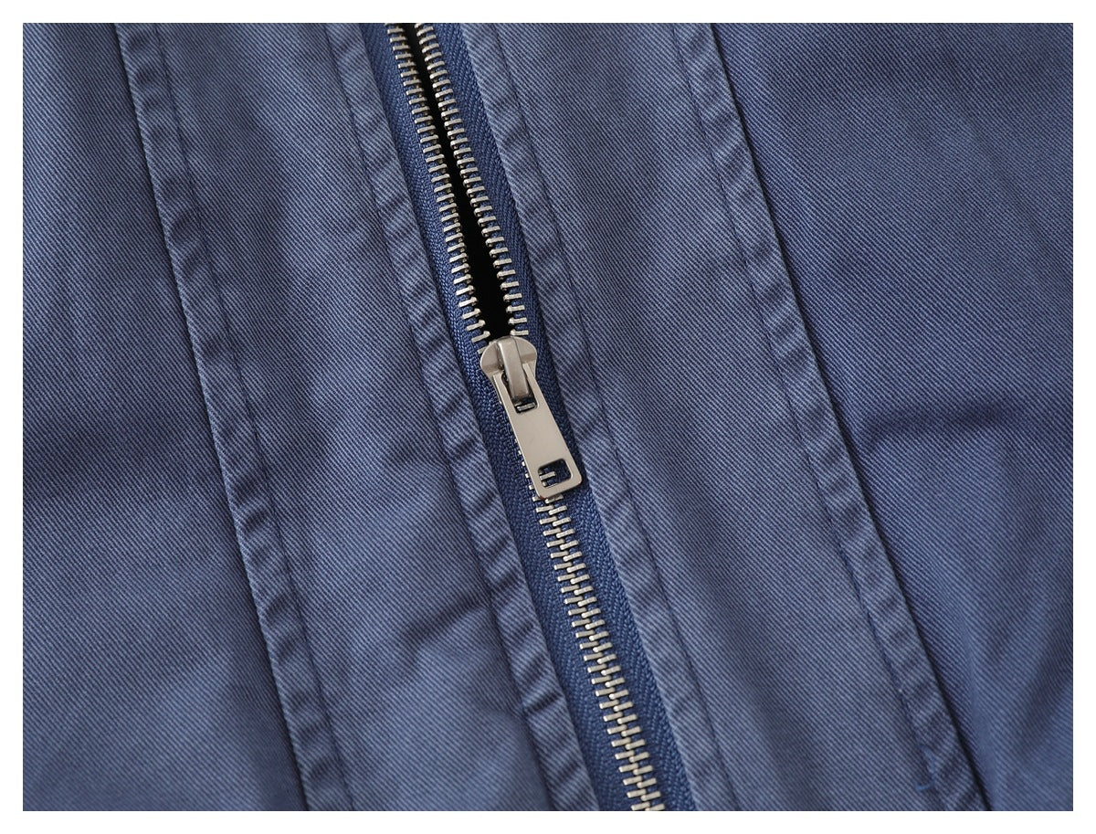 Close-up of the blue-gray jacket's open metal zipper and stitched front panels.