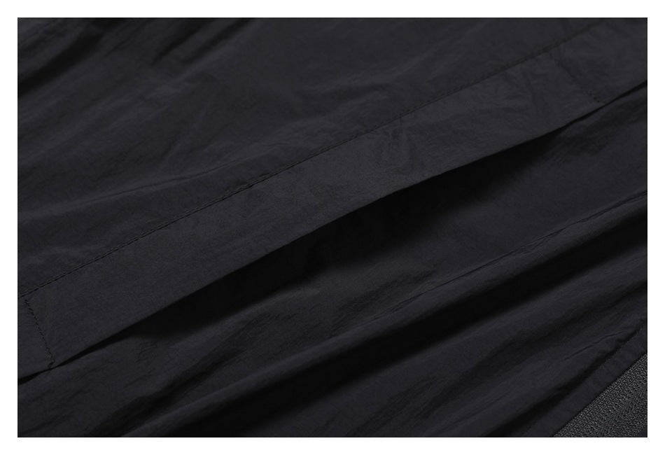 Close-up of seams and overlapping panels on black garment fabric.