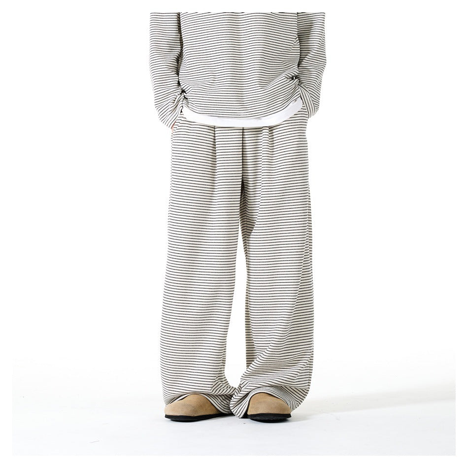 Person wearing beige striped wide-leg pants with matching striped top, white layer and tan suede clogs