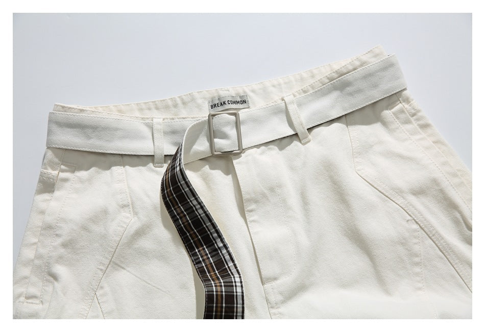 Cropped front view of ivory shorts with a square buckle belt and a dark brown plaid belt end.