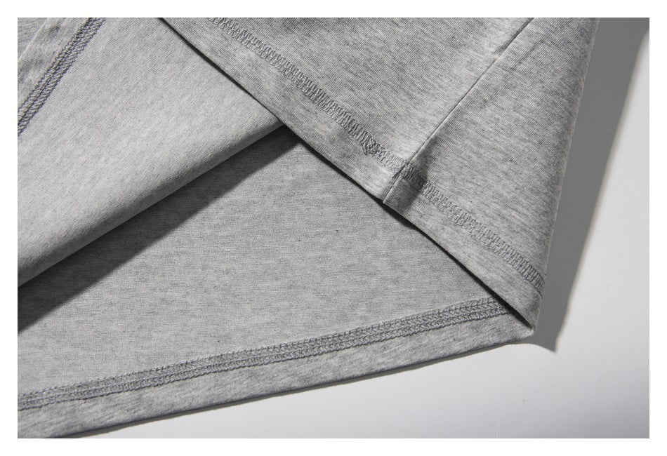 Close-up of the gray T-shirt's folded hem with visible overlock stitching.