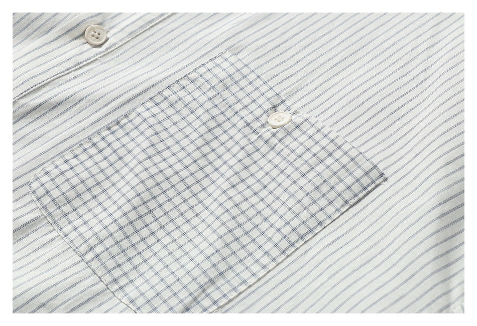 Close-up of a large checked chest pocket with a button against the shirt's fine gray vertical stripes.