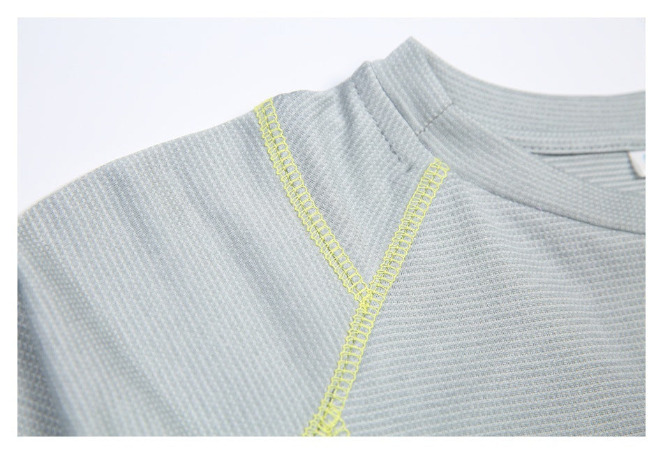 Close-up of the gray athletic top's shoulder seam and bright yellow overlock stitching.