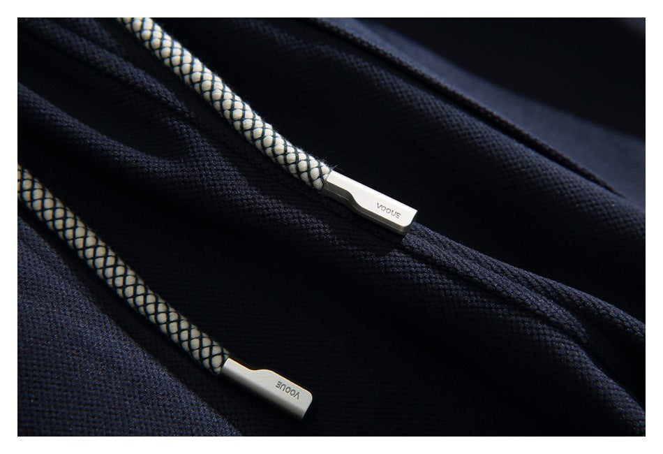 Close-up of navy pants with patterned drawcords and silver tips marked VOGUE.