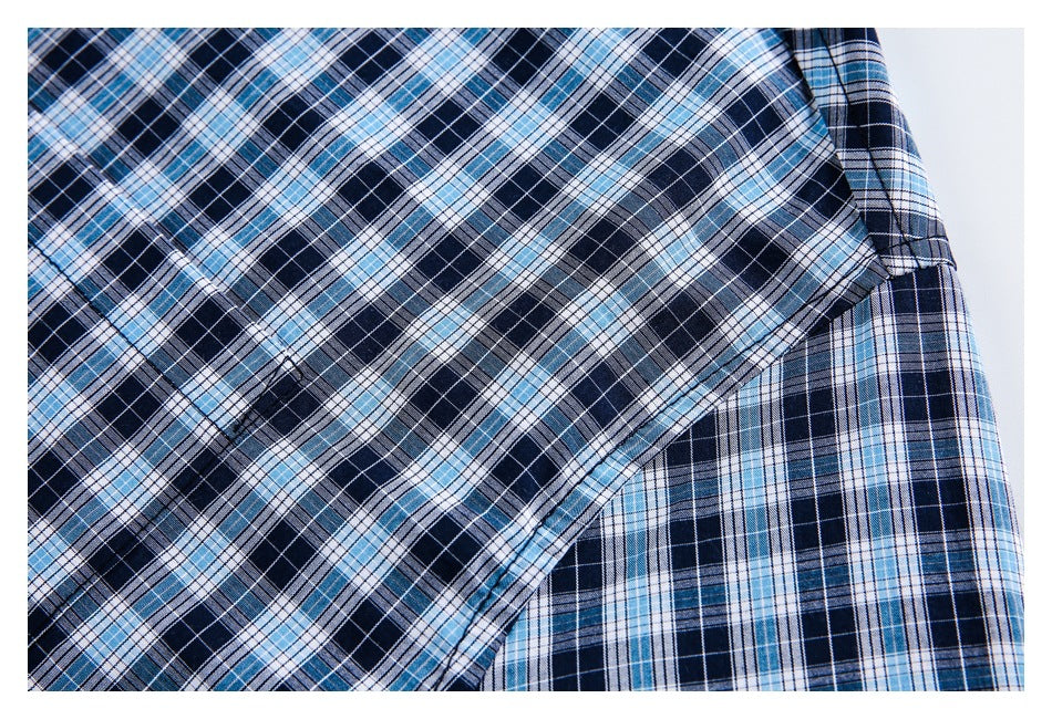 Close-up of the plaid shirt's stitched chest pocket against navy, light blue, and white checks.