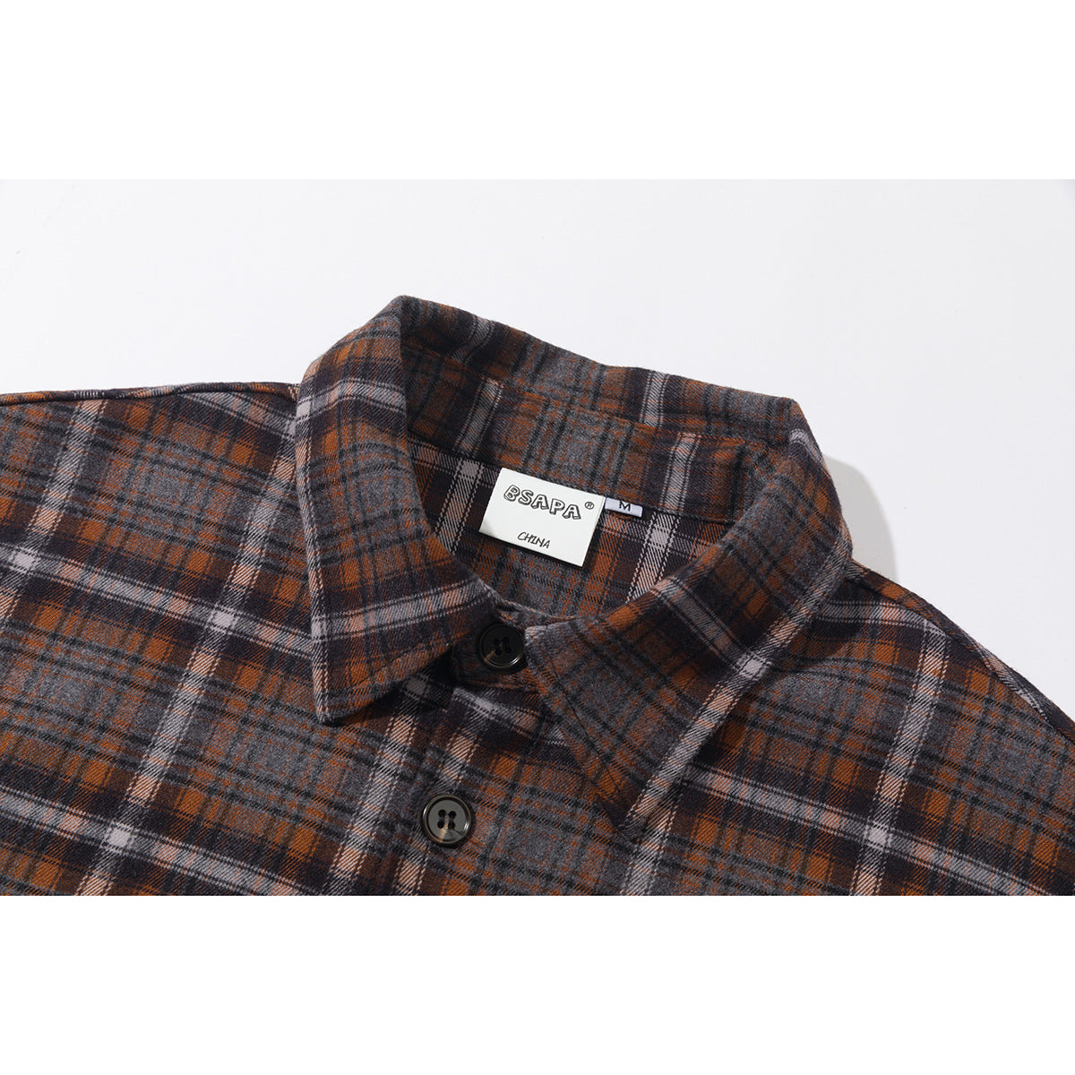 Close-up of a gray, rust, and black plaid shirt collar with dark buttons and a sewn neck label.