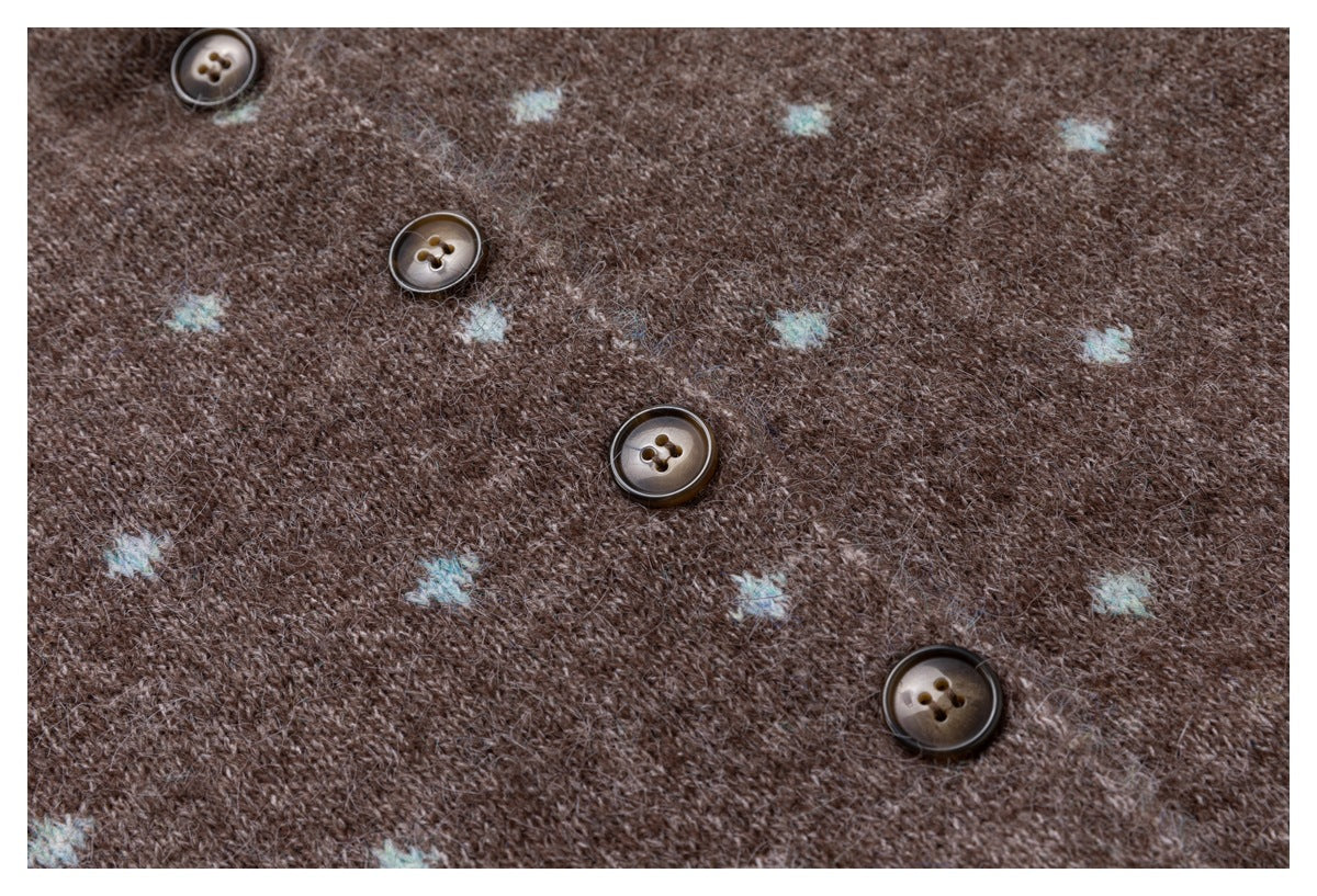 Close-up of a brown knit garment with small pale blue motifs and four brown buttons.