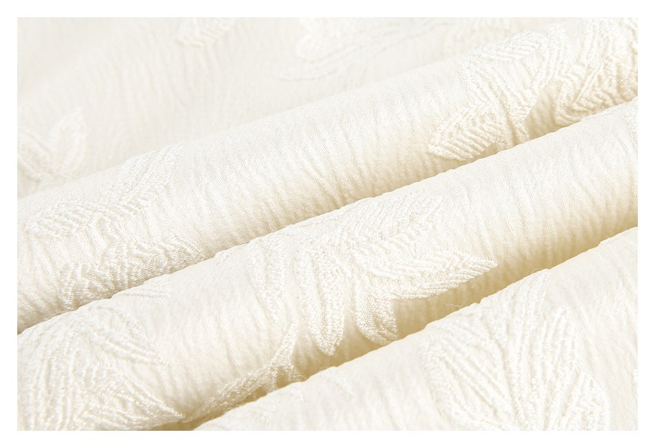Close-up of ivory fabric folds showing raised floral texture.