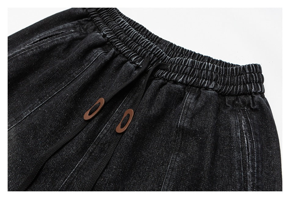 Close-up of black pants showing the gathered waistband and two brown oval accents.