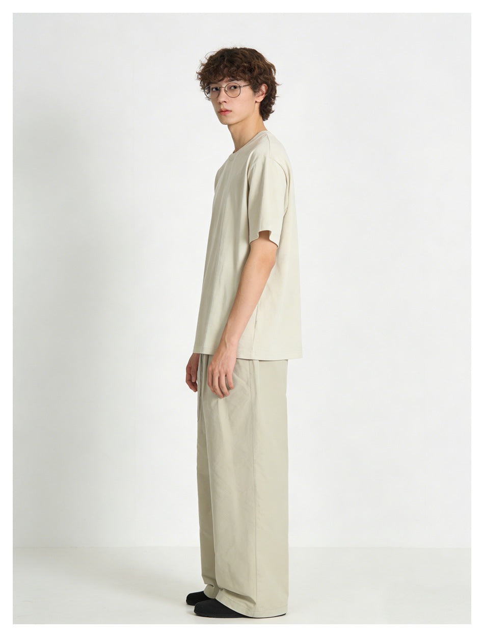 Side view of a model wearing an off-white oversized T-shirt and light beige wide-leg pants.