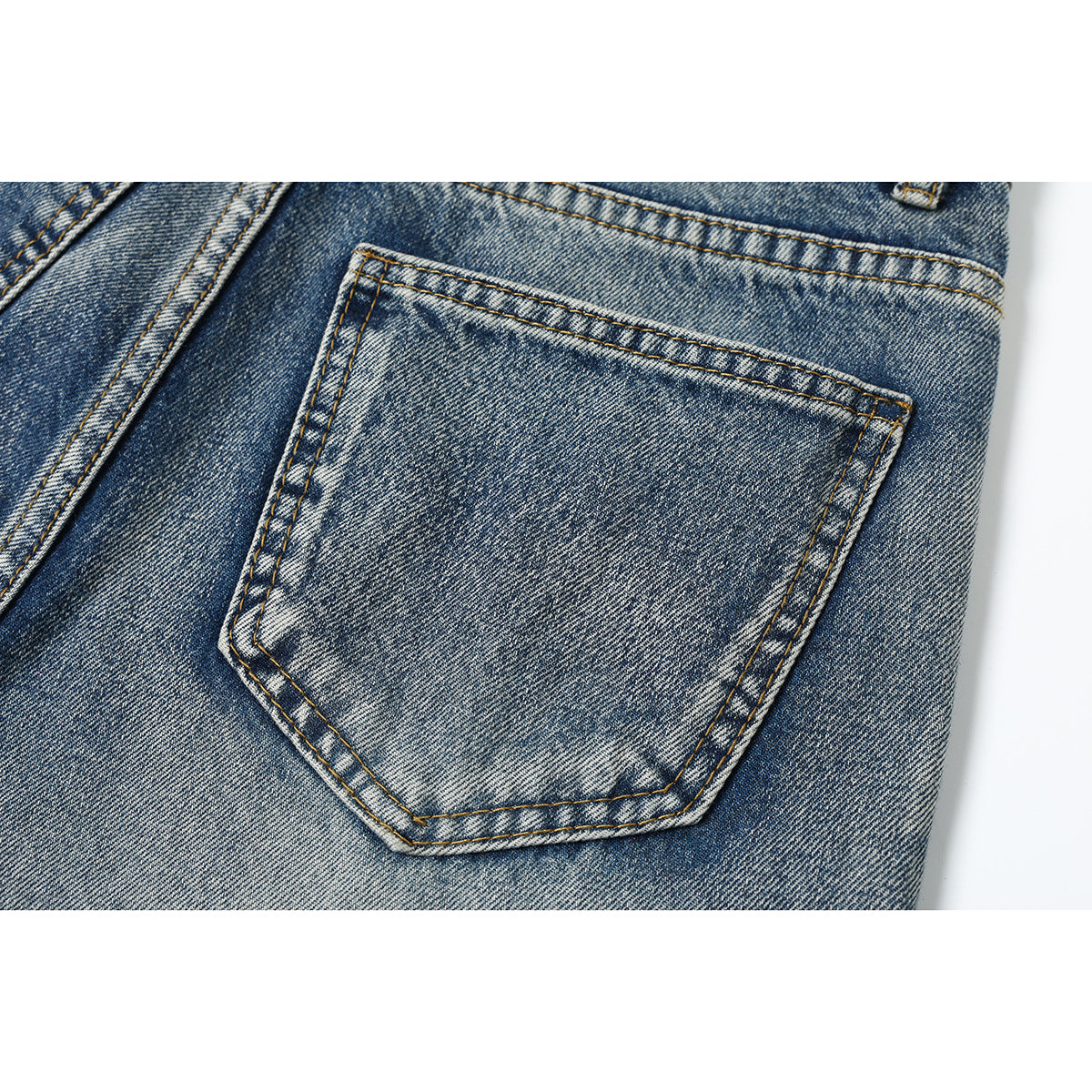 Close-up of a stitched back pocket on blue acid-wash jeans.