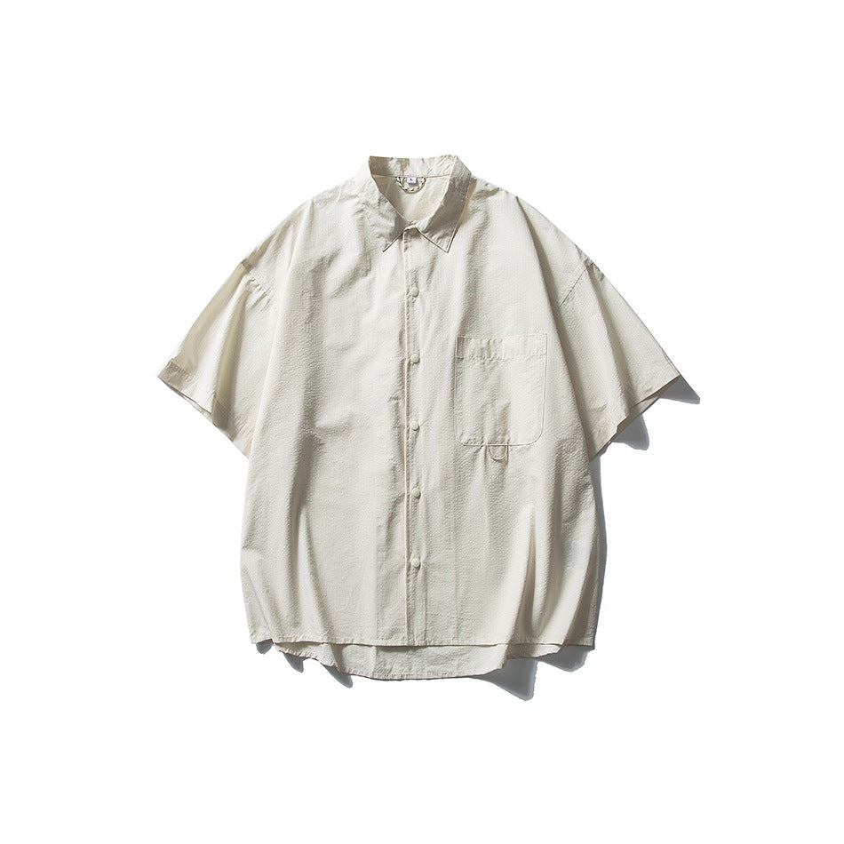 Cream short-sleeve button-front shirt with collar and chest pocket, flat lay on white background