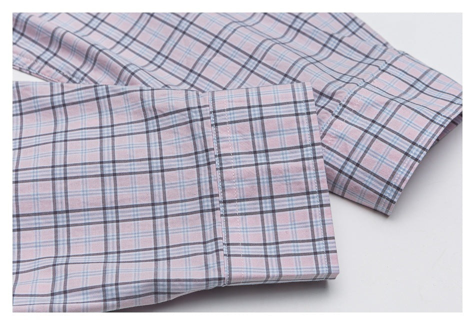 Close-up of a buttoned cuff and sleeve on a pale pink plaid shirt.