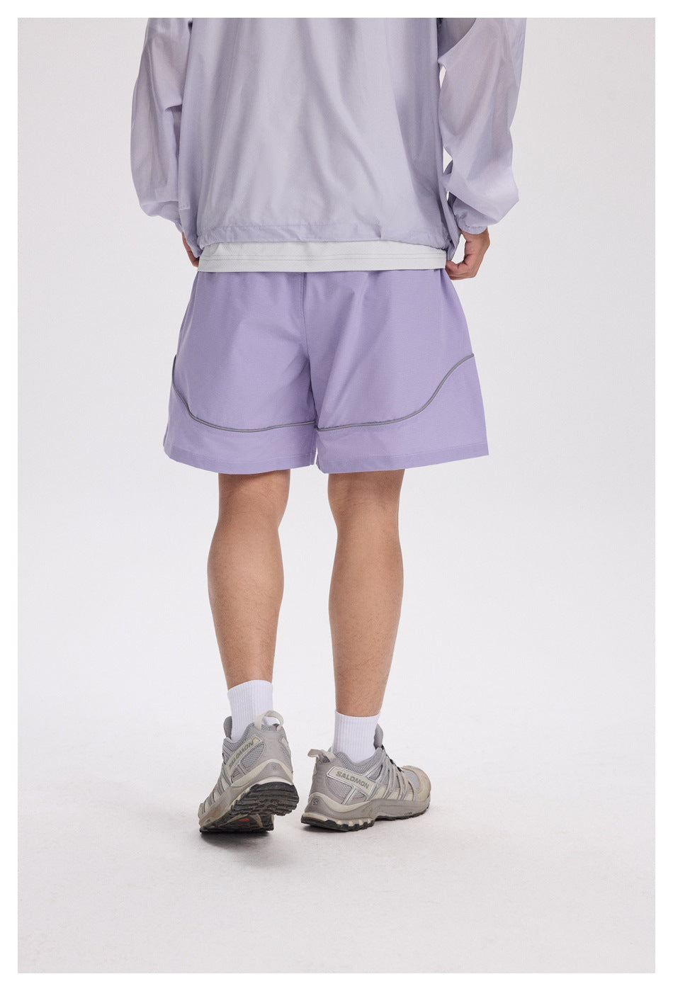 Back view of a person wearing lavender shorts with curved gray piping and wide hems.