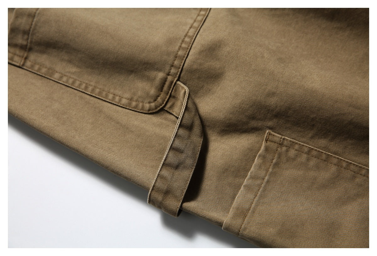 Close-up of brown pants showing a folded leg cuff, stitching and the edge of a patch pocket.