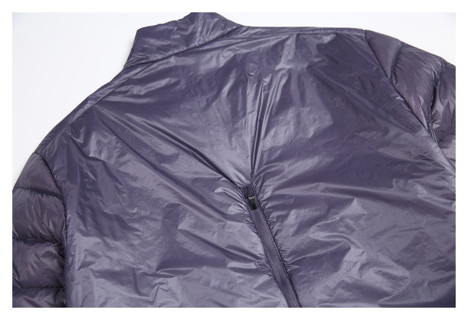 Back view of a dark purple quilted jacket laid flat, with a central zipper and padded sleeves.