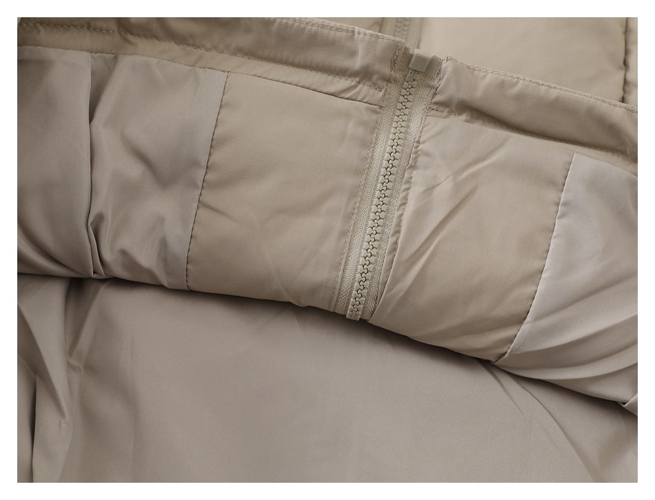 Close-up of a beige garment showing a central zipper, stitched panels, and gathered fabric.
