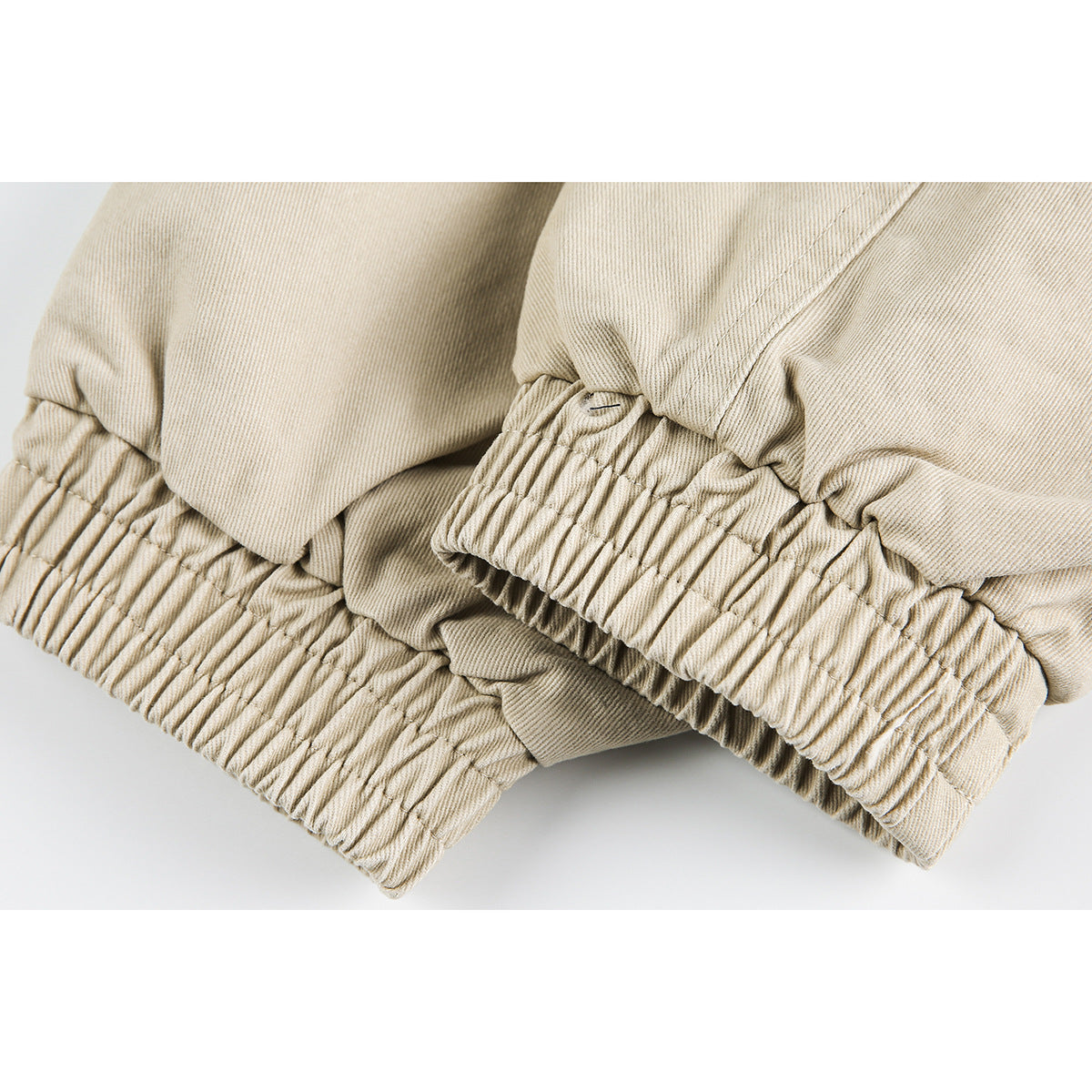 Close-up of the gathered elastic hem and stitched seams on a beige jacket.