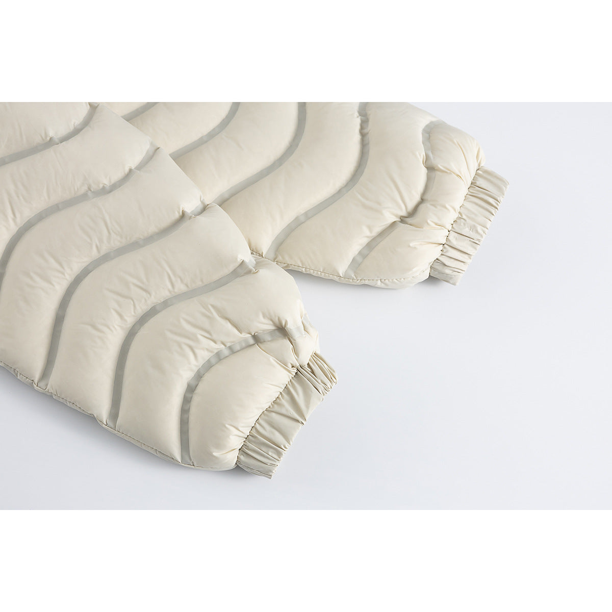 Close-up of the ivory jacket's wavy quilted sleeves and elastic cuffs.