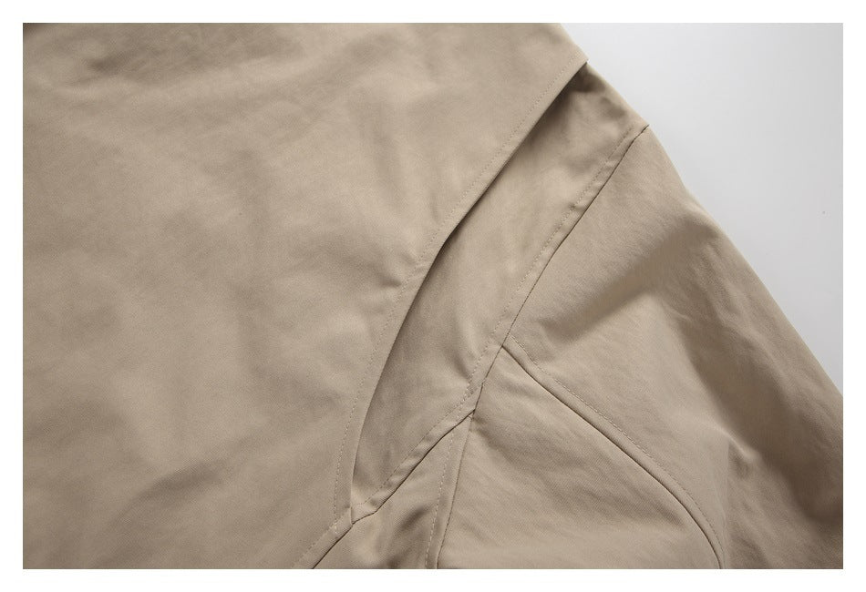 Close-up of beige garment seams and a curved pocket opening.