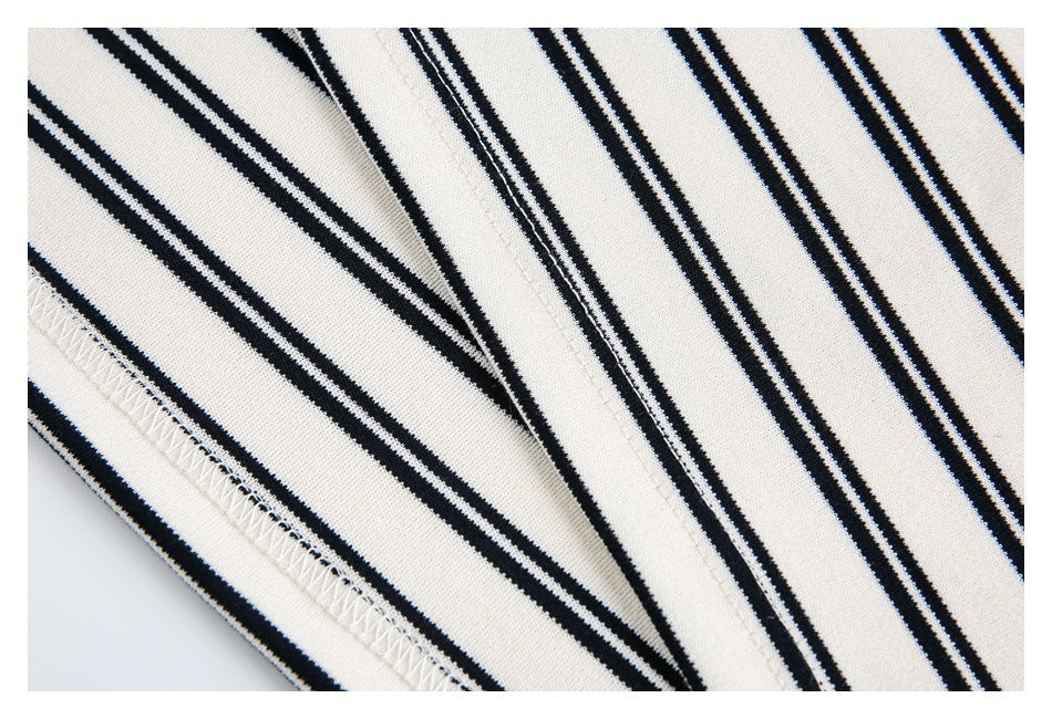 Close-up of ivory fabric with narrow black stripes and a stitched seam.
