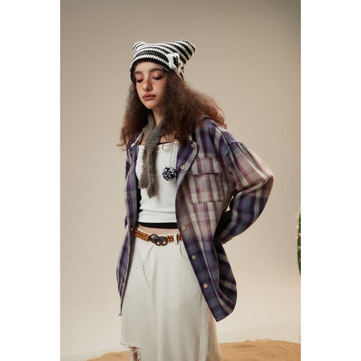 Model wearing an oversized purple, gray, and cream plaid snap-front shirt jacket with chest pockets.