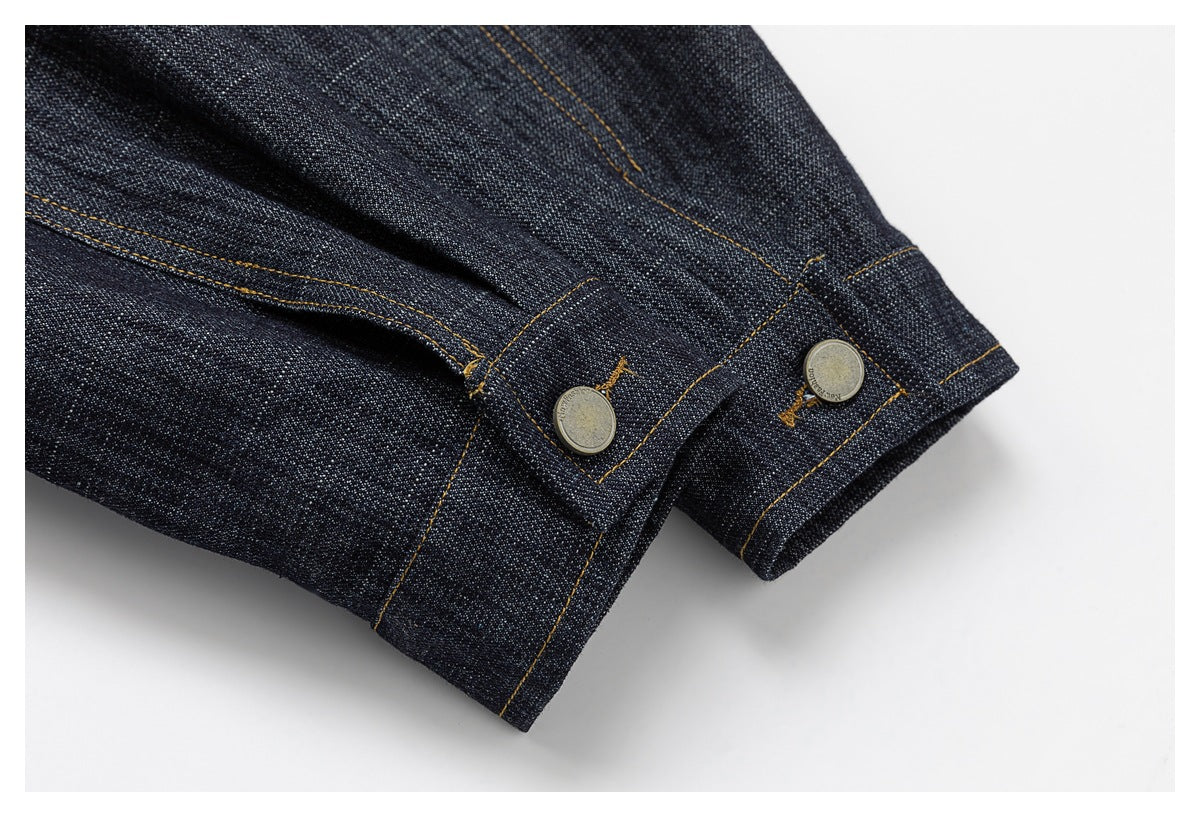 Close-up of dark denim cuffs with ochre stitching and metal-button tabs.