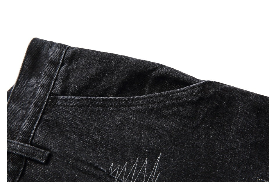 Close-up of black denim shorts showing the waistband, belt loop, seam, and decorative stitching.
