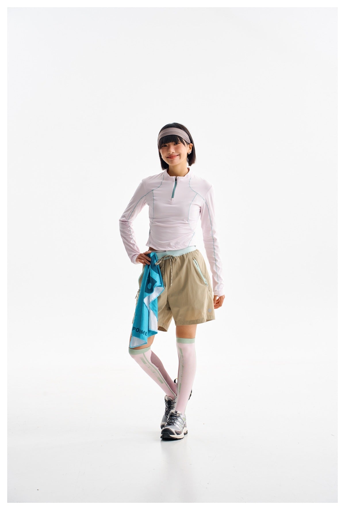 Model wearing a pale pink long-sleeve quarter-zip top and tan drawstring shorts, shown in a relaxed pose.