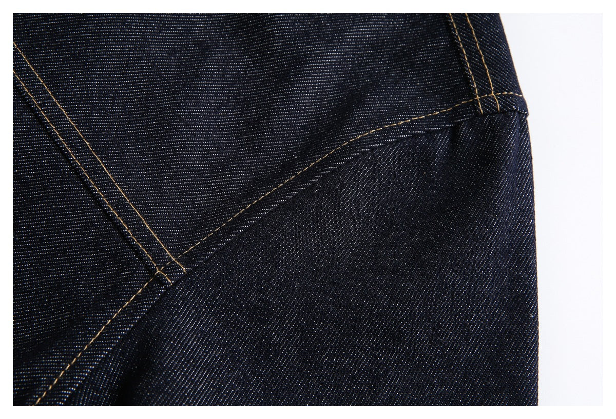 Close-up of dark indigo denim showing a curved seam and parallel tan topstitching.